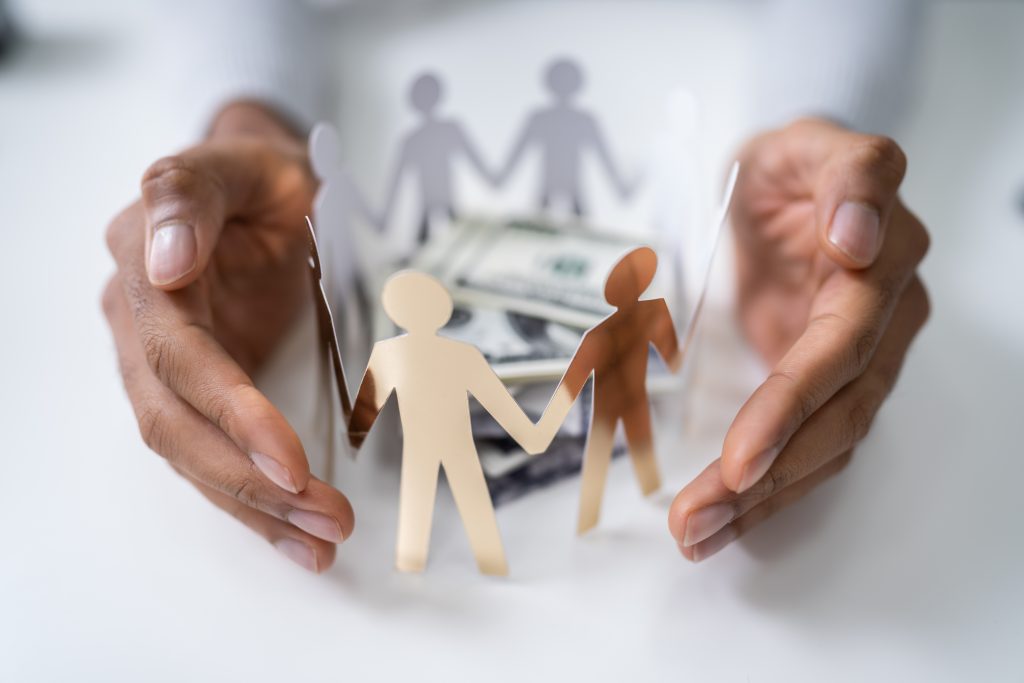 Person's Hand Protecting Stacked Banknotes Surrounded By Human Figures